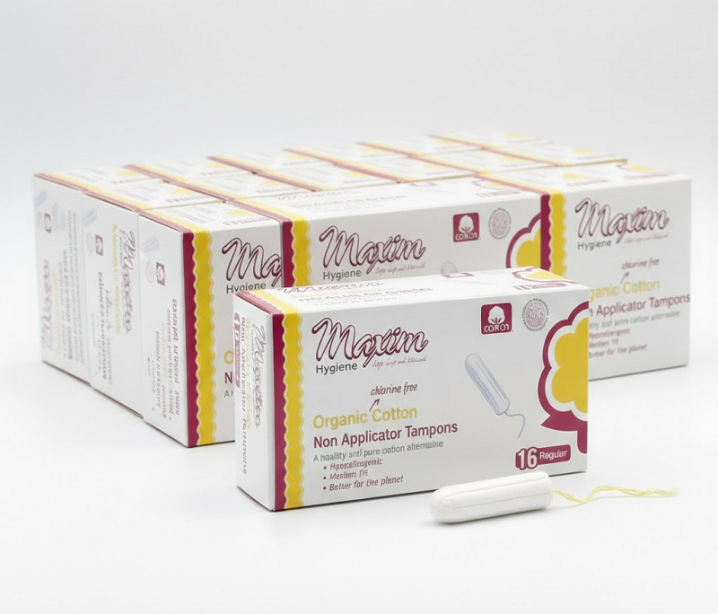 A sealed case containing 12 packs of Maxim® 100% Certified Organic Cotton Non-Applicator Tampons in Super Plus absorbency, totaling 192 individual tampons. The packaging prominently features the brand, product type, and key certifications.