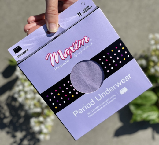 Hand holding Maxim period underwear boyshorts package in lavender with medium absorbency, reusable leak-proof menstrual underwear.