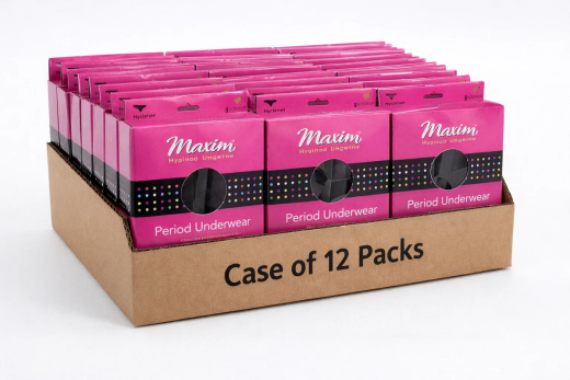 Person holding two Maxim period underwear boxes one pink and one lilac with circular fabric windows, photographed outdoors in natural sunlight.
